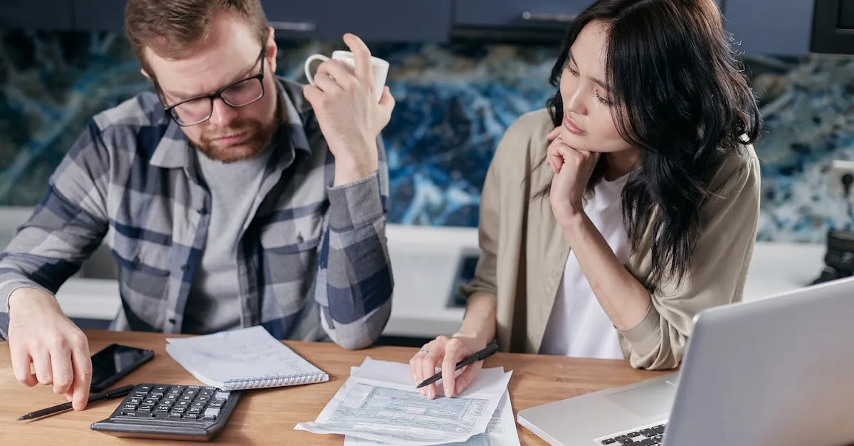 Homem e mulher analisam papéis e calculadora em mesa de trabalho.