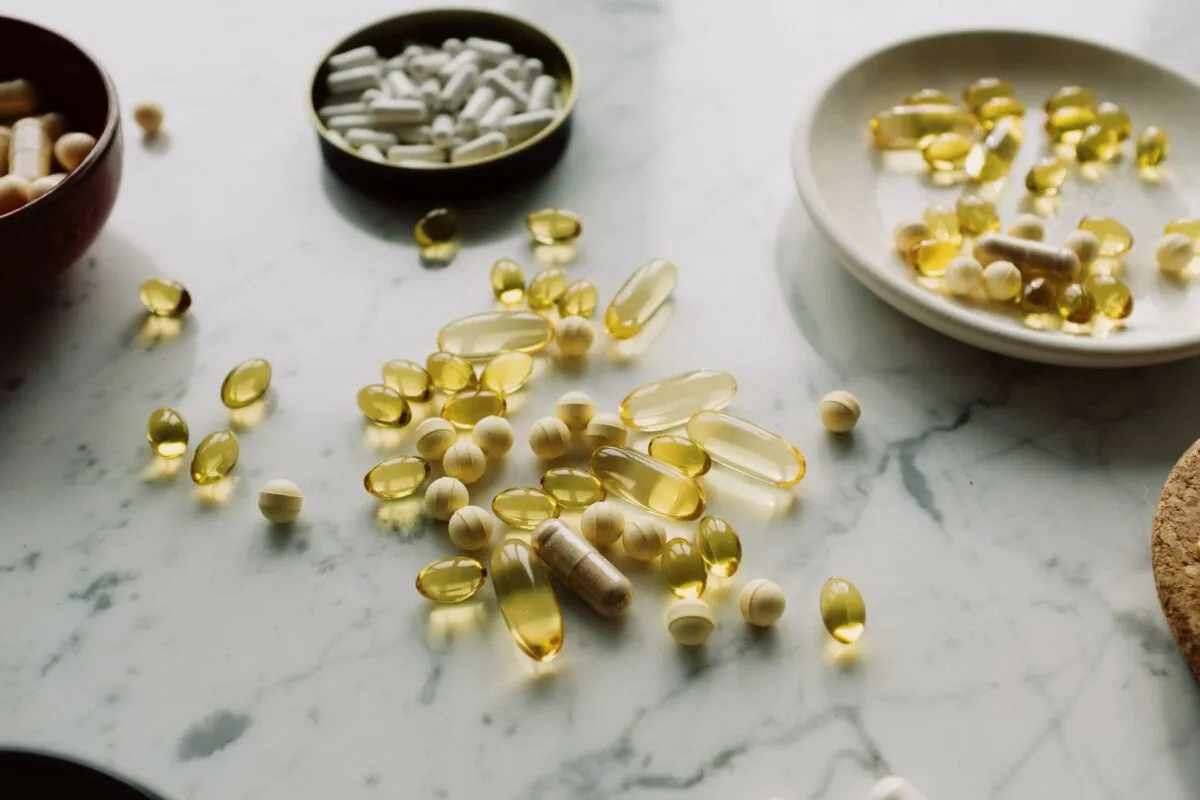 Cápsulas de óleo, comprimidos e tigelas com suplementos alimentares espalhados em uma bancada de mármore